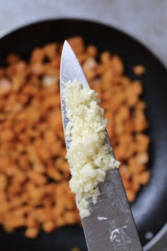 chopped garlic being added to the diced sweet potato