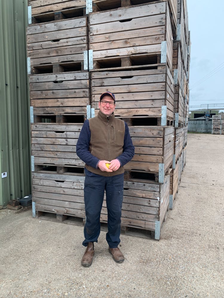 John our apple grower standing in front of apple crates