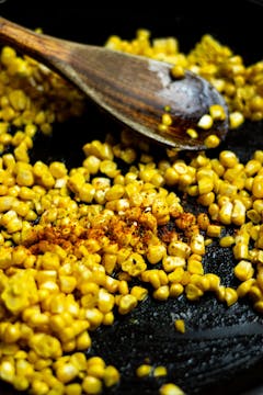 Corn kernels frying with chilli flakes.
