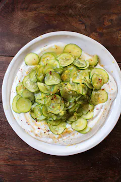 thinly sliced courgette on a white base of ricotta