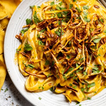 close up of creamy butternut squash pasta with parsley and chilli flakes on top 