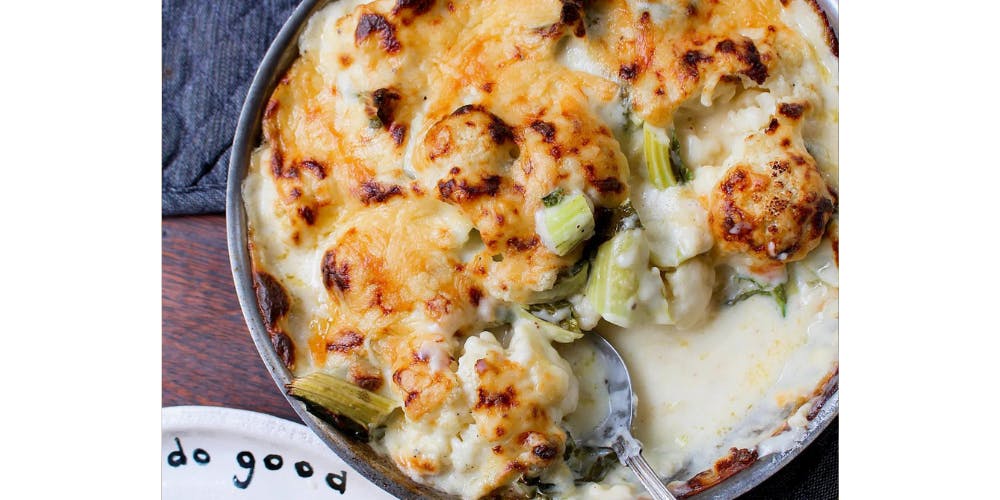 Cauliflower cheese being served with a spoon 