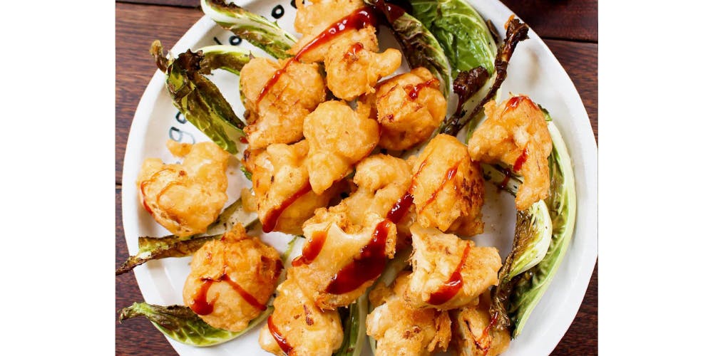 Cauliflower nuggets on a white plate with crispy cauliflower leaves