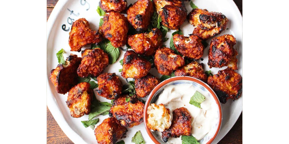 Cauliflower wings on a white plate with a dipping sauce