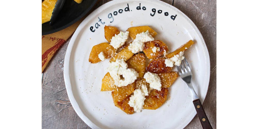 Grilled pineapple topped with coconut cream on a white plate