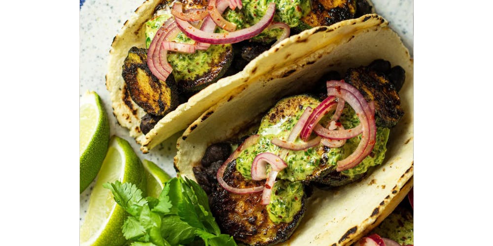 Courgette tacos dressed with coriander and lime wedges