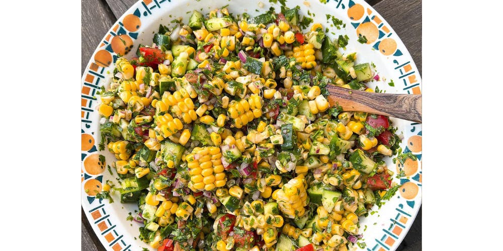Corn salad with a wooden spoon in the bowl