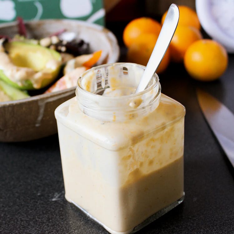 Clementine and tahini dressing in a jar with a spoon