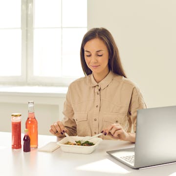 woman at her desk eating lunch