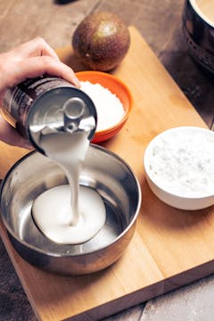 coconut milk being poured into a pot