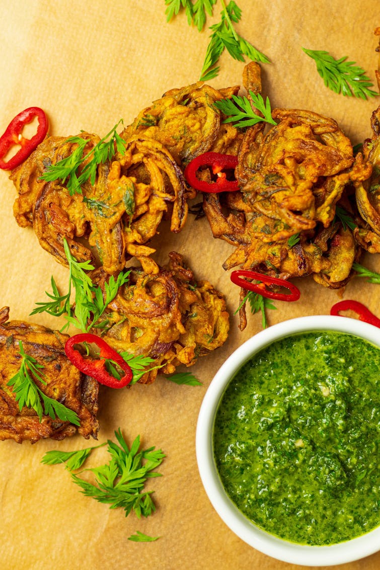 6 spicy carrot and onion bhaji garnished with red chilli slices and coriander leavers. on the side green chutney