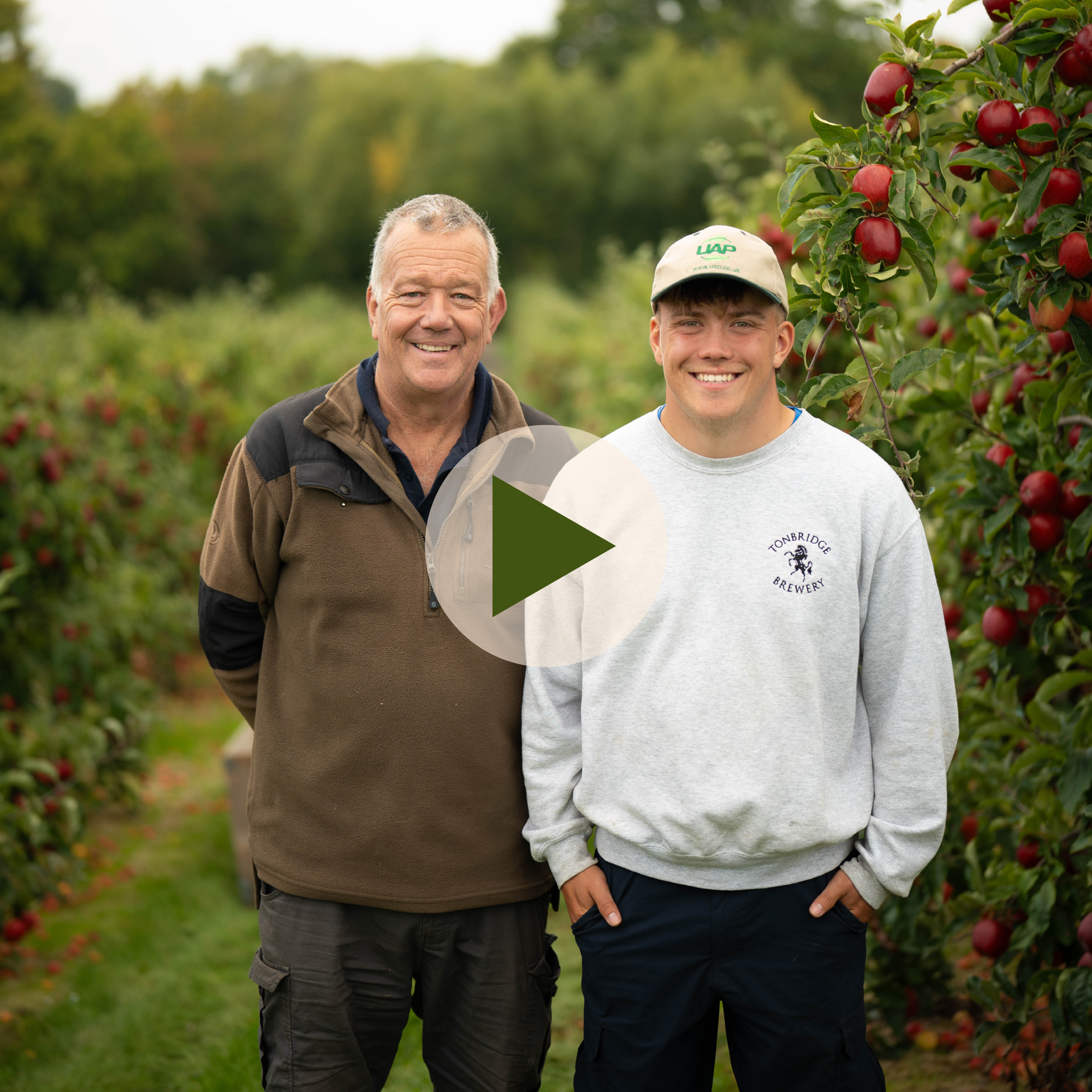 Northiam Farm Growers - father and son smiling to camera with video play button overlaid.