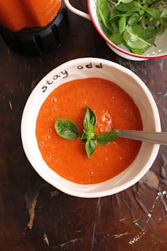 Roasted bell paper gazpacho served in bowl, garnished with basil