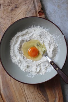 in a mixing bowl, pasta flour and one cracked egg and fork for mixing.