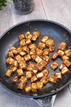 Tofu fried until crispy in a pan. 