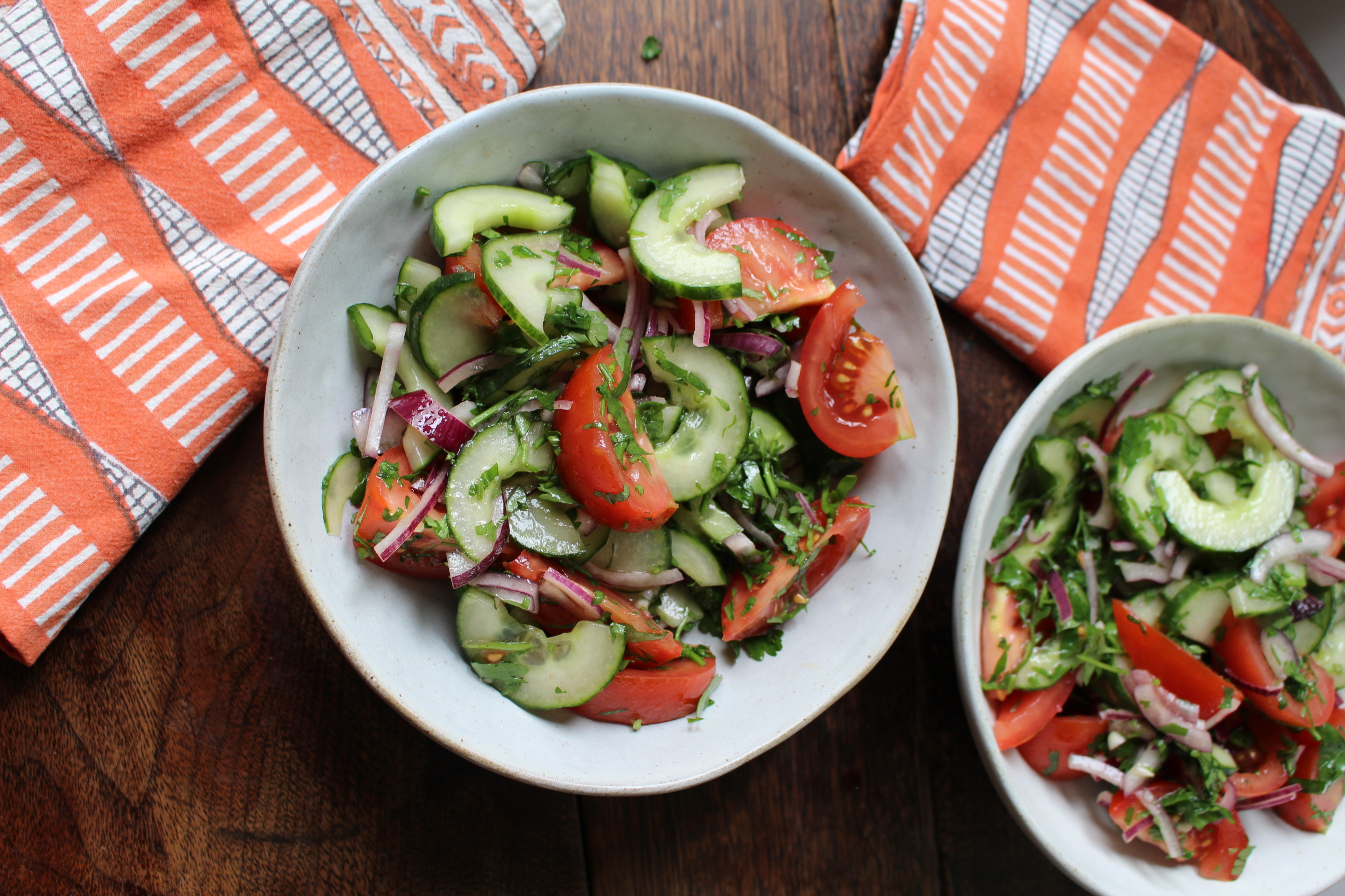 two white bowls with cucumber and tomato salad