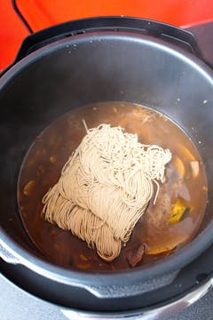 ramen noodles being added to a pressure cooker