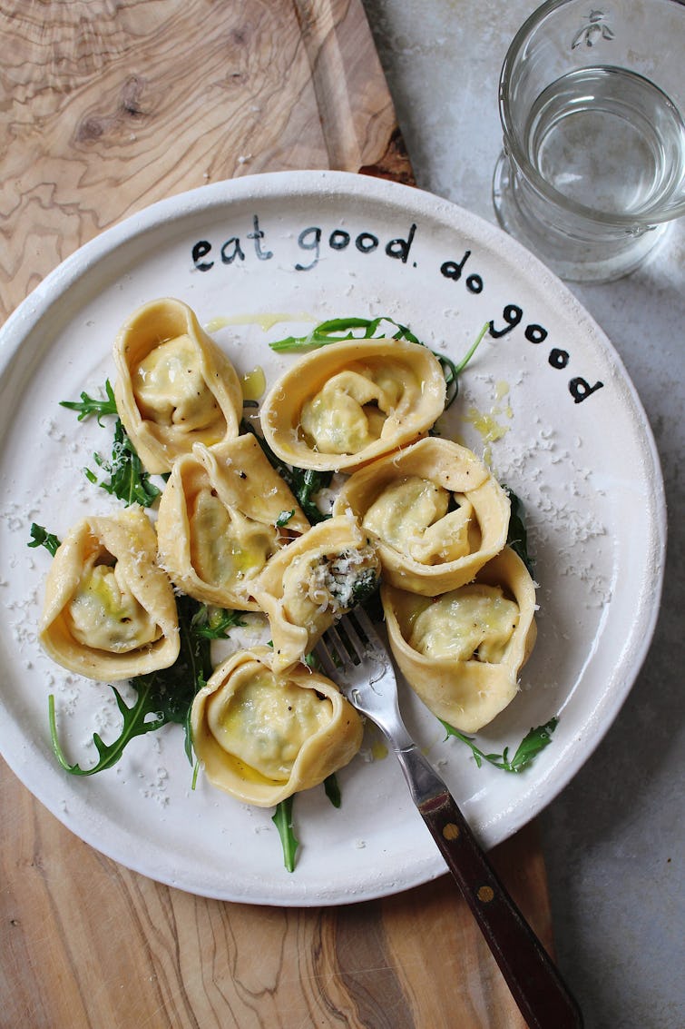 cooked Tortellini served with grated  parmesan cheese on a plate and fork
