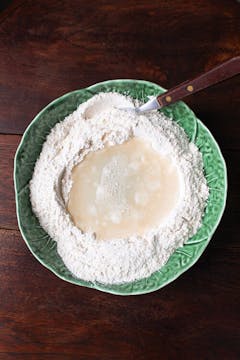 Water in a well of flour, to be mixed to make potsticker dough. 