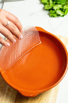 Rice paper being soaked in warm water in a bowl. 