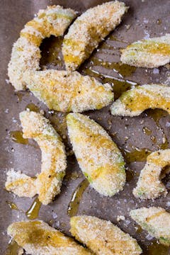 breaded avocado on a baking tray  drizzled with oil