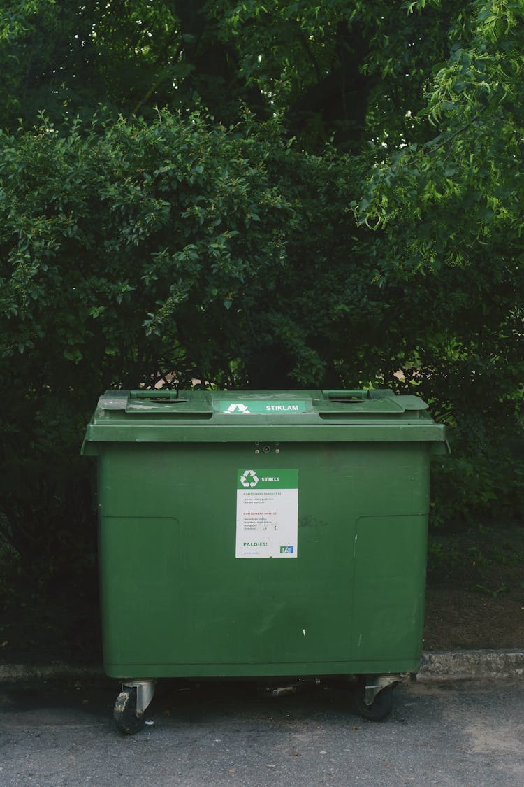 recycling bin in front of green bushes