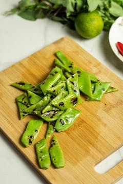 Chopped and blistered flat beans on a chopping board.