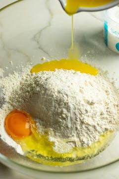 The ingredients for the empanada dough in a bowl. Butter and egg are being mixed with flour and salt. 