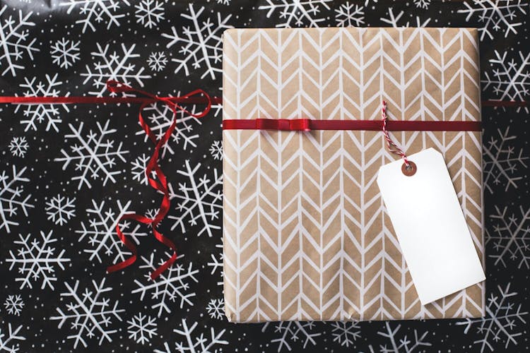 A wrapped Christmas present, with a red ribbon around it. There's an empty tag attached to it.