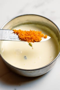 on a sauce pan, double creme, cardamon pods and orange zest on a knife about to be added to the saucepan