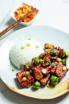 white rice, sprouts and tofu sprinkled with sesame seeds and sliced spring onion on a plate. Small side of kimchi