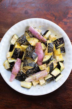 chopped up aubergine and shallot in a white bowl with seasonings