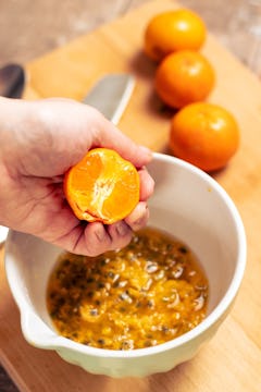 in a bowl passionfruit puree and half of an clementine being squeezed 