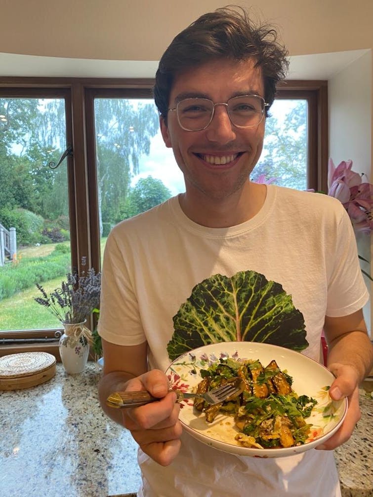 Oddbox employee Drew holding a plate of baked miso aubergine and cabbage 