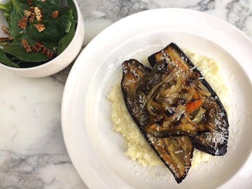 Annie Bell's Roasted Vegetables with Parsnip and Parmesan Mash & Spinach Salad. The roast vegetables and mash are on a plate, with the spinach salad served separately in a bowl.