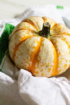 An orange pumpkin rested on a dishcloth. 