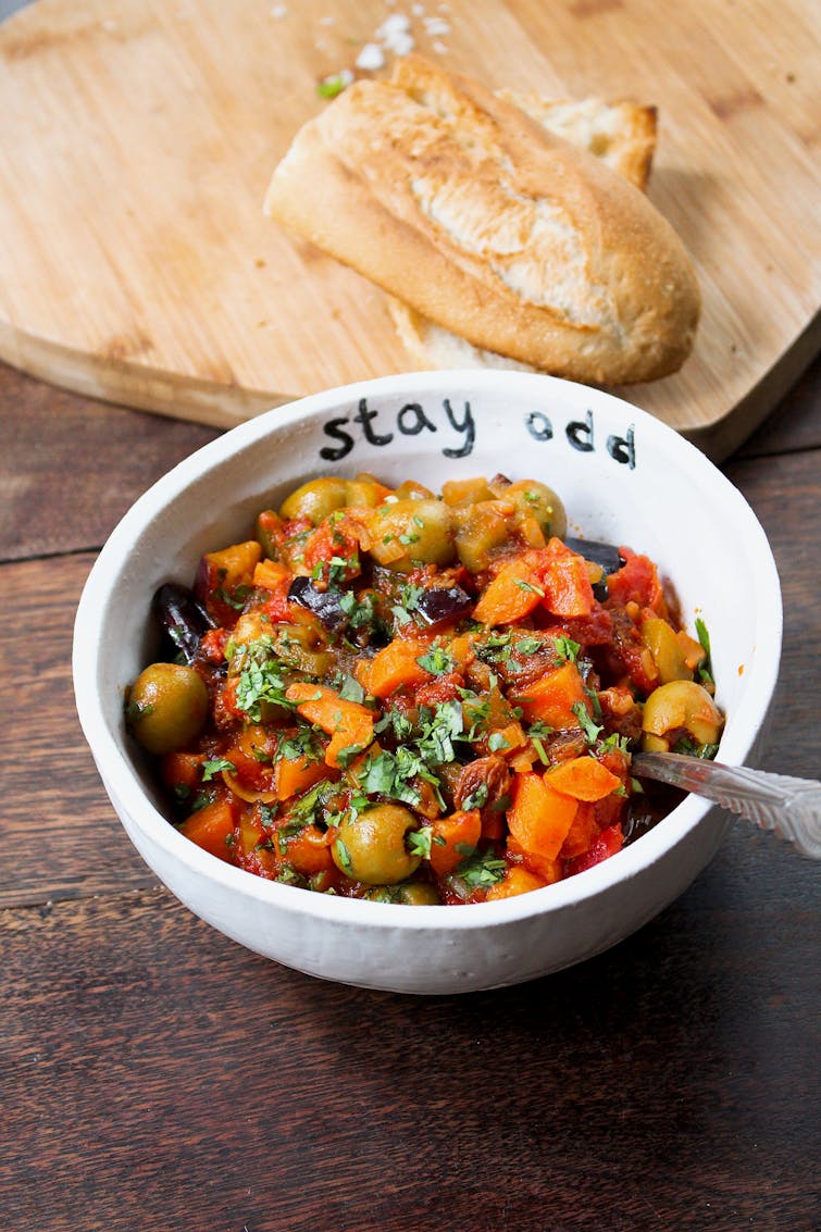 carrot caponata in a white bowl with crusty bread served on the side