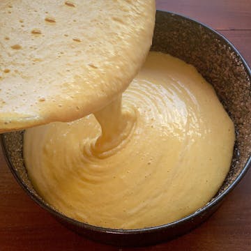 cake mix pouring into cake tin which has been coated with demerara sugar 