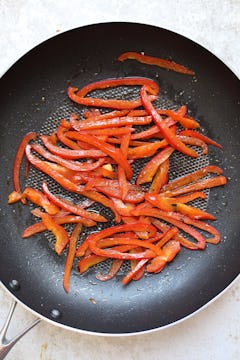 Chopped peppers being fried in a pan. 