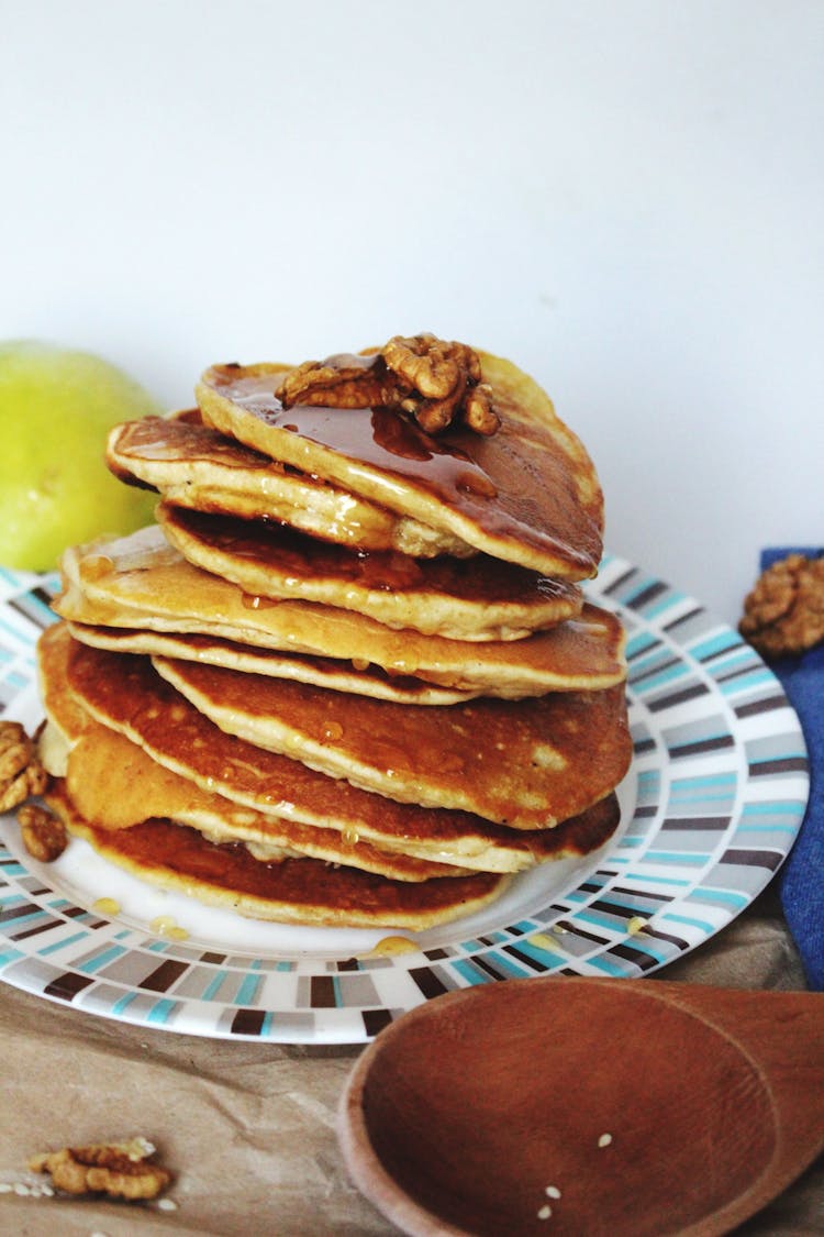 stack of pancakes drizzled with syrup and walnut
