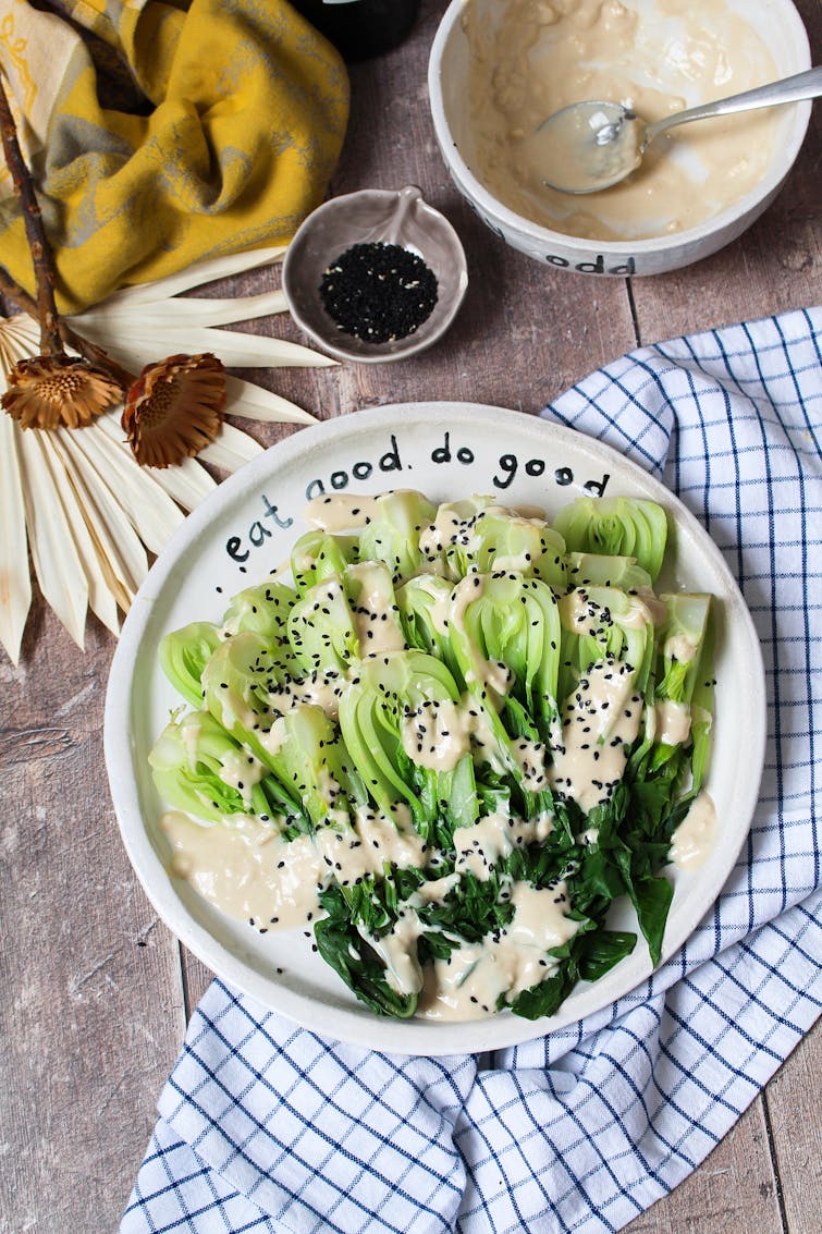 plate of Pak Choi with toasted sesame dressing, blue and white square cloth, toasted back sesame seeds and sesame dressing