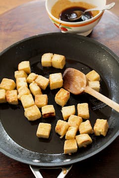 Tofu being crisped in a frying pan