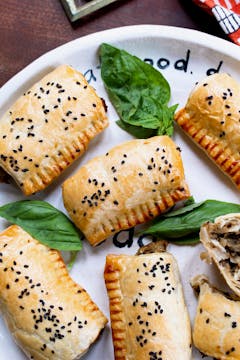 miso aubergine sausage rolls with basil leaves on a white plate