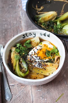 A serving of pak choi noodles with a runny egg on top. 