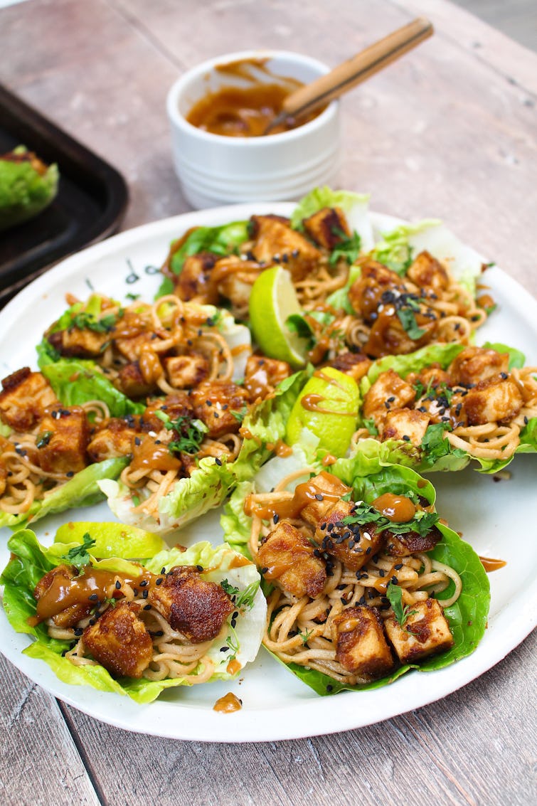 A plate of peanut butter tofu lettuce wraps with a bowl of sauce. 