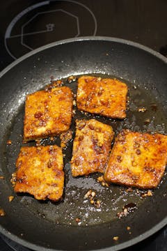 slices of tofu being grilled in a pan 