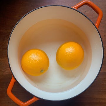 2 boiling oranges in a pan with orange handles