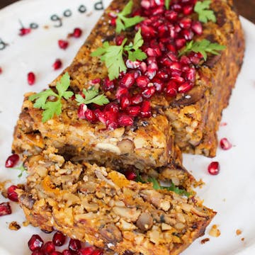 nut roast on a white plate topped with pomegranate seeds