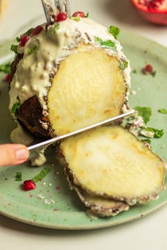 Celeriac Shawarma with Pomegranate, Mint & Tahini Dressing being sliced 