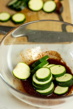 in a bowl, sliced courgettes being marinated in the spice 